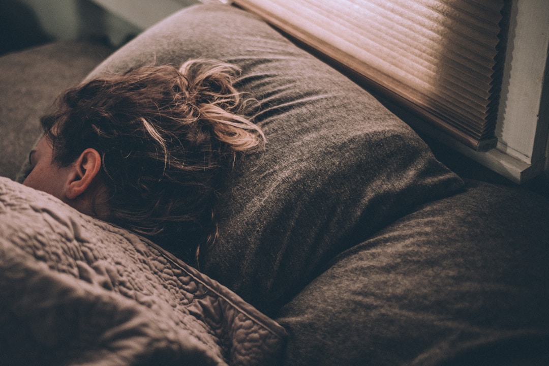 A person sleeping in a darkened bedroom, illustrating the raw data collection phase that feeds the calibration algorithm over the first two weeks