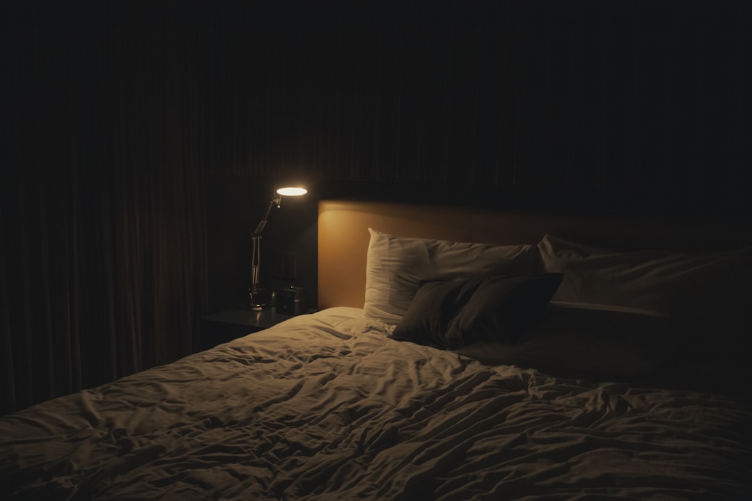 A hotel room at night with an unmade bed, representing the unfamiliar environment where the first night effect occurs and sleep trackers get confused