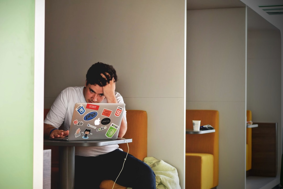 A person sitting at a desk with their head in their hands, surrounded by screens. This posture produces a low HRV reading, but the wearable blames it on stress rather than posture or breathing